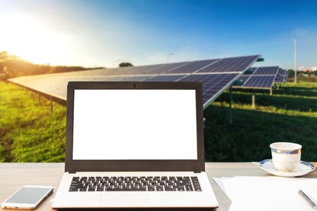 Mockup image of laptop with blank blank screen,smartphone,coffee cup on wooden table of solar panel...