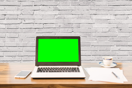 Mockup image of laptop with blank green screen,smartphone,coffee cup on wooden table of coffee wall large texture background.の写真素材