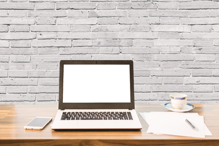 Mockup image of laptop with blank white screen,smartphone,coffee cup on wooden table of coffee wall large texture background.の写真素材