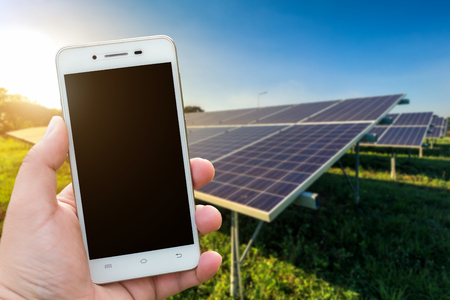 Men use smartphone blurred images in the solar panel background. As Renewable Energy and clean energy.の写真素材