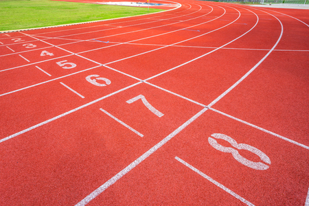 White lines of stadium and texture of running racetrack red rubber racetracks in outdoor stadium are 8 track and green grass fieldの写真素材