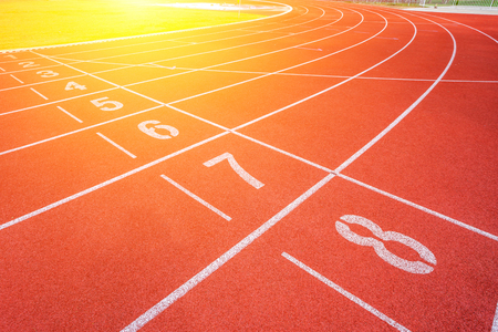 White lines of stadium and texture of running racetrack red rubber racetracks in outdoor stadium are 8 track and green grass fieldの写真素材