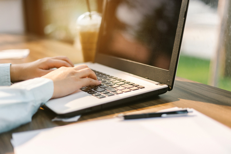 Close-up of business female working with laptop make a note document and smartphone in coffee shop like the background.の写真素材