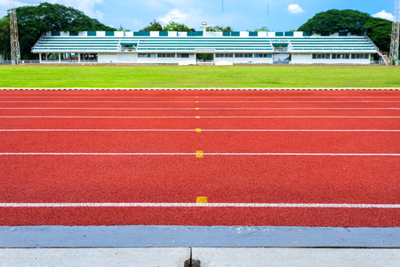 White lines of stadium and texture of running racetrack red rubber racetracks in outdoor stadium are 8 track and green grass fieldの写真素材