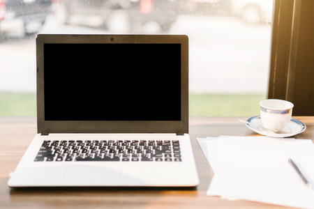 Mockup image of laptop with blank black screen,smart phone and document on wooden table of In the coffee shop.の写真素材