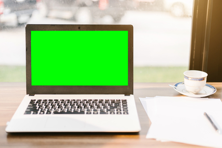 Mockup image of laptop with blank green screen,smartphone,coffee cup on wooden table of In the coffee shop.の写真素材