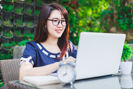 Happy business Asian woman working with laptop computer and clock,notebook on office outdoorの写真素材