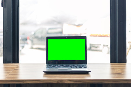 Mockup image of laptop with blank black screen on wooden table of In the coffee shop