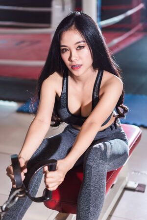 Fitness Asian women performing doing exercises training with rowing machine (Seat Cable Rows Machine) in sport gym interior and fitness health club with sports exercise equipment Gym background.の写真素材
