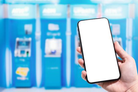 Close-up of female use Hand holding smartphone blurred images touch of Abstract blur in Blurred of ATM machine blue in Department store. for background usage.の写真素材