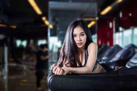 Fitness Asian women performing doing exercises training the run on treadmill in sport gym interior and health club.の写真素材