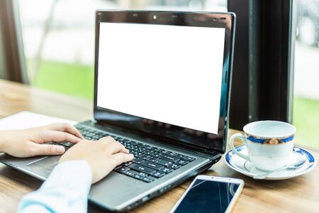 Close-up of Business woman working with smartphone,laptop with blank white screen and document in coffee shop like the background.の写真素材