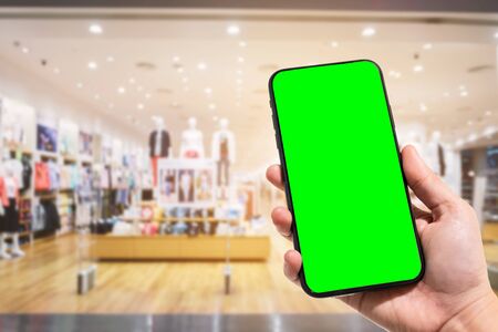 Close-up of female use smartphone blurred images in the mall and Clothes shop blur of the background.の写真素材