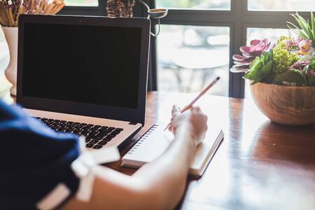 Close-up of business female working with laptop make a note in coffee shop like the background.の写真素材