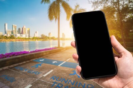 Close-up of female use smartphone blurred images in road pathway in the park for relaxing walking jogging or ride bicycle and exercise at Cityscape blur of the background.の写真素材