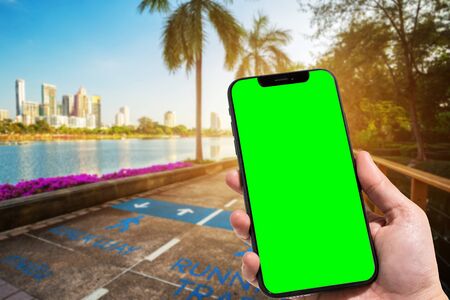 Close-up of female use smartphone blurred images in road pathway in the park for relaxing walking jogging or ride bicycle and exercise at Cityscape blur of the background.の写真素材