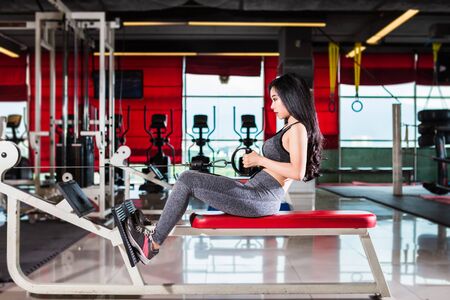 Fitness Asian women performing doing exercises training with rowing machine (Seat Cable Rows Machine) in sport gym interior and fitness health club with sports exercise equipment Gym background.の写真素材