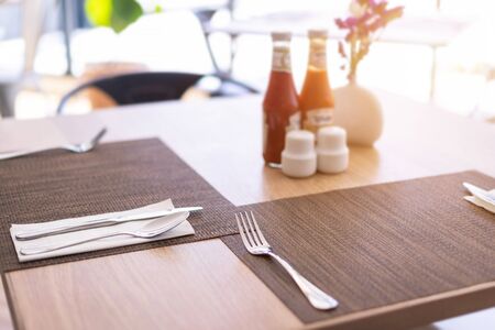 Close-up of luxurious spoon and fork, flower vaseson, sauce bottle the dining table decoration in hotelの写真素材