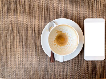 Smartphone and Empty coffee cup on wood desk on top view.の写真素材