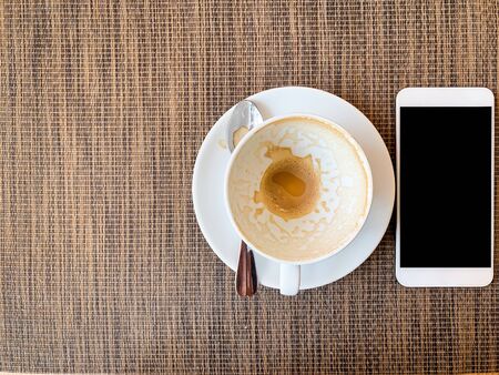 Smartphone and Empty coffee cup on wood desk on top view.の写真素材
