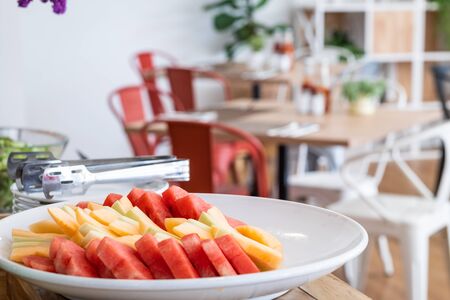 Chop the pieces of watermelon and pineapple in white dish the dining and flower vase on table decorationat buffet self service at hotel.の写真素材