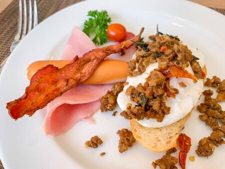 Breakfast, Kaprao fried pork with herb leaf on top Poached egg with bacon on toast, food thai.の写真素材
