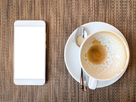 Smartphone and Empty coffee cup on wood desk on top view.の写真素材