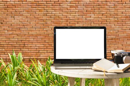 Mockup image of laptop with blank black screen with camera,notebook,coffee cup on wooden table with wall large texture background.の写真素材