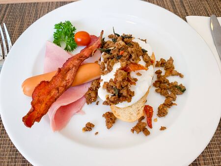 Breakfast, Kaprao fried pork with herb leaf on top Poached egg with bacon on toast, food thai.の写真素材