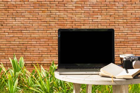 Mockup image of laptop with blank black screen with camera,notebook,coffee cup on wooden table with wall large texture background.の写真素材