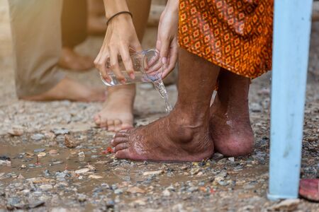 Hand of pouring water on the foot of revered elders and ask for blessing happy for the songkran festival in Thailand, Traditional Thailand New Year.の写真素材