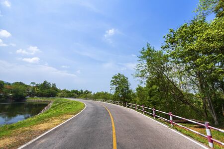 road view reservoir green tree with green nature forest in the hill and blue sky background.の写真素材