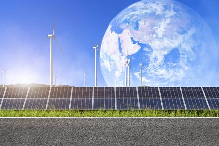 Asphalt road with solar panels with wind turbines against mountanis landscape in earth blue sky with...
