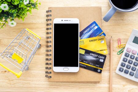 Smartphone on Credit cards,notebook,flower pot tree,Shopping cart,calculator and coffee cup on...