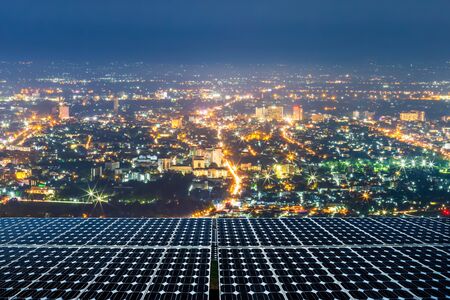 Solar panel or Photovoltaic modules solar power plant with cityscape over the light of city center background at night time, Alternative energy concept.の写真素材