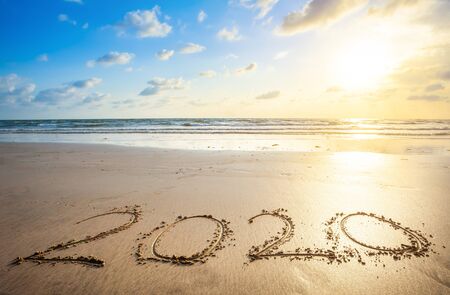 Happy New Year 2020 text on beautiful the sea beach with wave early morning sunrise over the horizon...