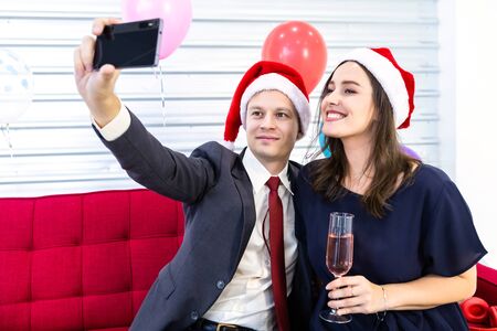 Happy new year 2020 concept, Selfie of Happy couple holding the champagne glass in Christmas and New Year's Eve party Christmas tree background After finishing business workの写真素材