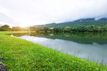 green grass landscape lake views at Ang Kaew Chiang Mai University in nature forest Mountain views spring blue sky background with white cloud.の写真素材