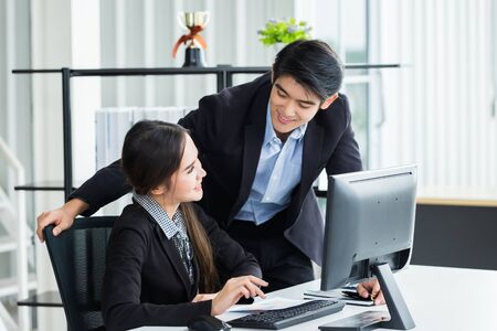 Happy of businesswoman and businessman partners discussing positive adult business working together with computer on wooden table and ideas at meeting in office background.の写真素材