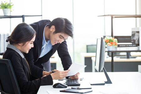 Happy of businesswoman and businessman partners discussing positive adult business working together with computer on wooden table and ideas at meeting in office background.の写真素材