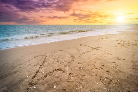 Happy New Year 2021 text on beautiful the sea beach with wave early morning sunrise over the horizon background.During Christmas and New Year.の写真素材
