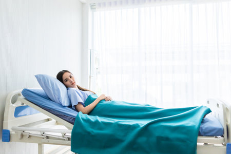 One asian young female patient With anxiety face lying on bed in the room hospital background.の写真素材