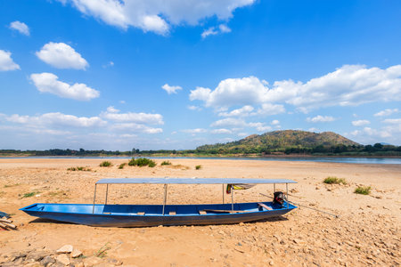 Boat parked in on the dry sand ground of Mae Khong river with Mountain views of Laos at the Kaeng Khud Khu rapids at Chiang Khan in Loei province,Thailand.の写真素材