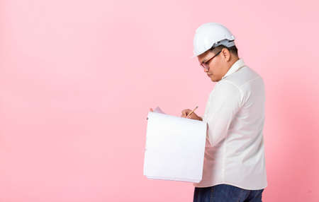 Industry worker or engineer working an architect builder studying layout plan serious civil engineer working with reading on blueprint isolated on pink blank copy space studio background,indoor studioの写真素材