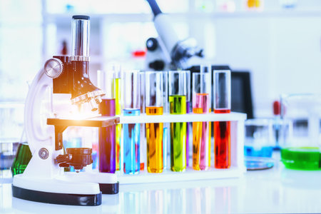 Microscope and Colorful test tubes with lab glassware in laboratory background, research and Scientific conceptの写真素材