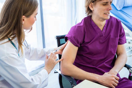 Close-up of female doctor with syringe to the arm of a man patient  on Bed for better healing In the...