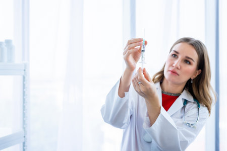 female doctor with stethoscope with holding a syringe in Hospital backgroundの写真素材