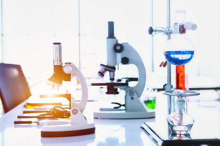 Microscope and test tubes with lab glassware in laboratory background, research and Scientific...
