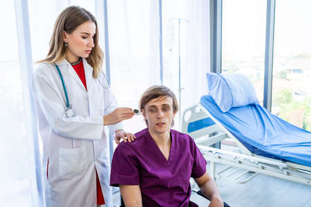 female doctor checking man patient's temperature in the ear with Tympanic Thermometer on Bed with Digital pressure gauge for better healing In the room hospital background.の写真素材
