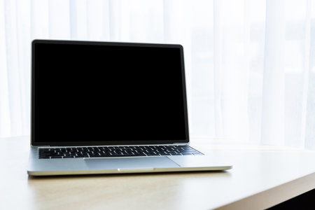 Mockup of Laptop computer with white blank screen on wooden table interior at the window In the office room background,Work business conceptの写真素材